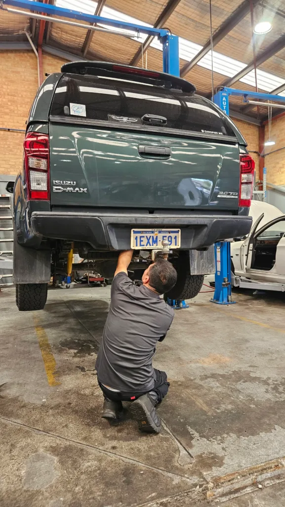 Sell My Car Pro technician working under an Isuzu D-Max on the hoist