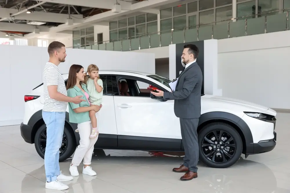 Smiling salesman with clipboard showing new car finance