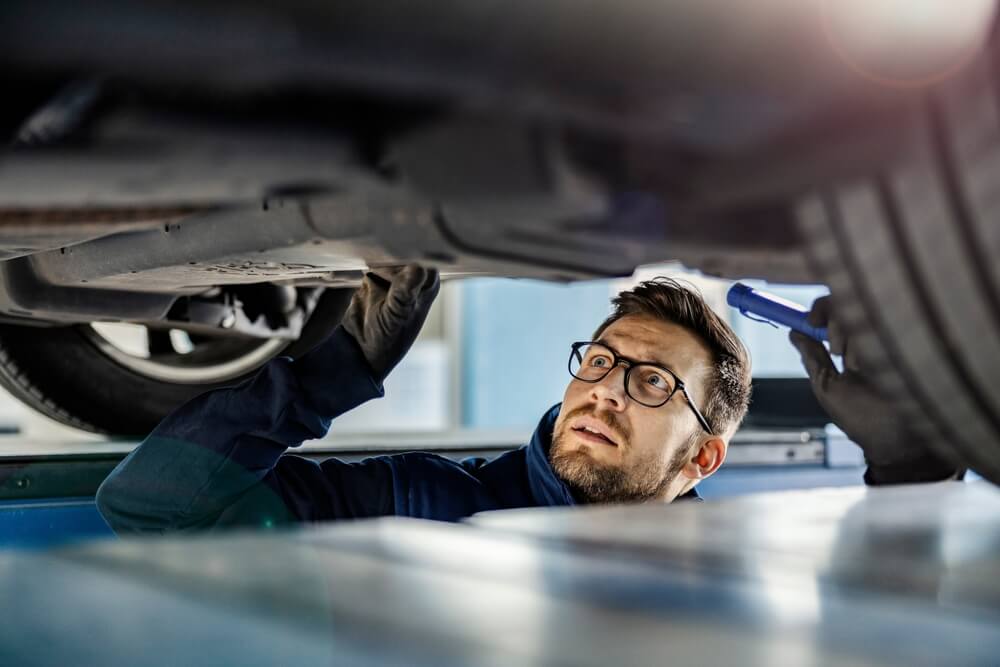 mechanic inspector looking under a car in garage