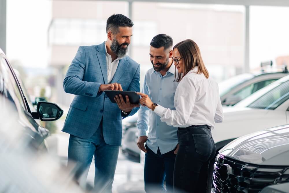 A couple and a car salesman negotiating a car at a dealership