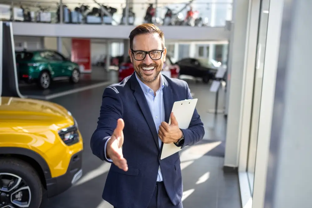 Young confident car sales man reaching out for a handshake