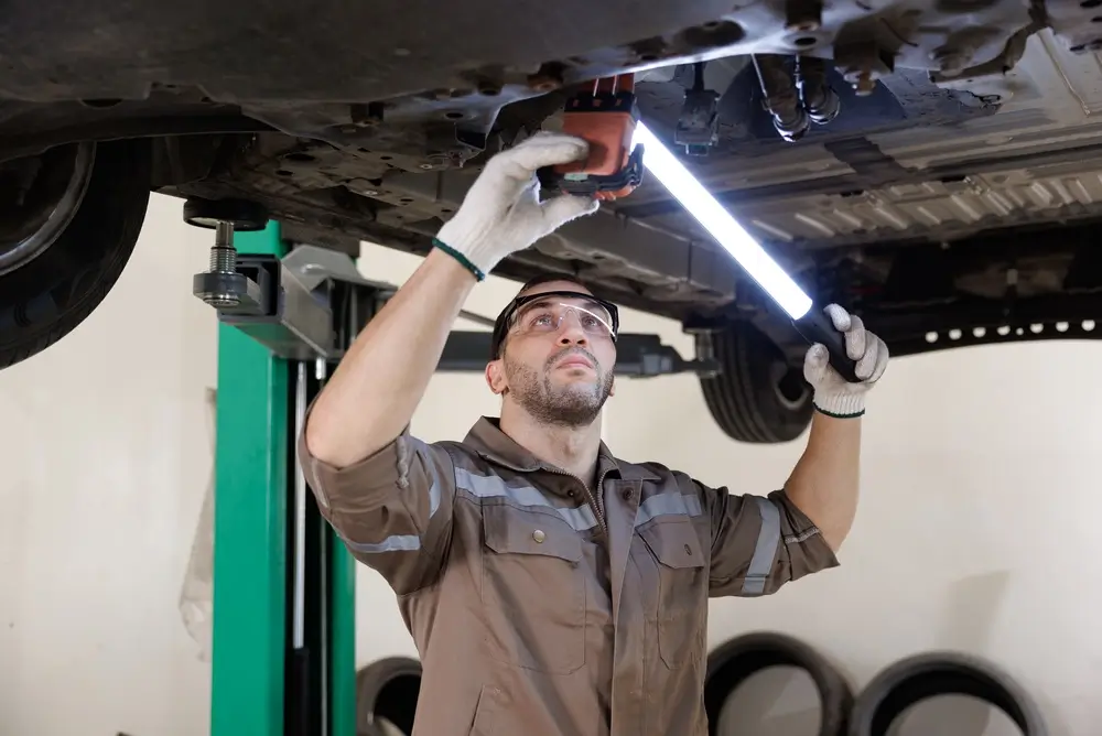 Technician inspecting a vehicle on a hoist in the Sell My Car Pro workshop in Malaga